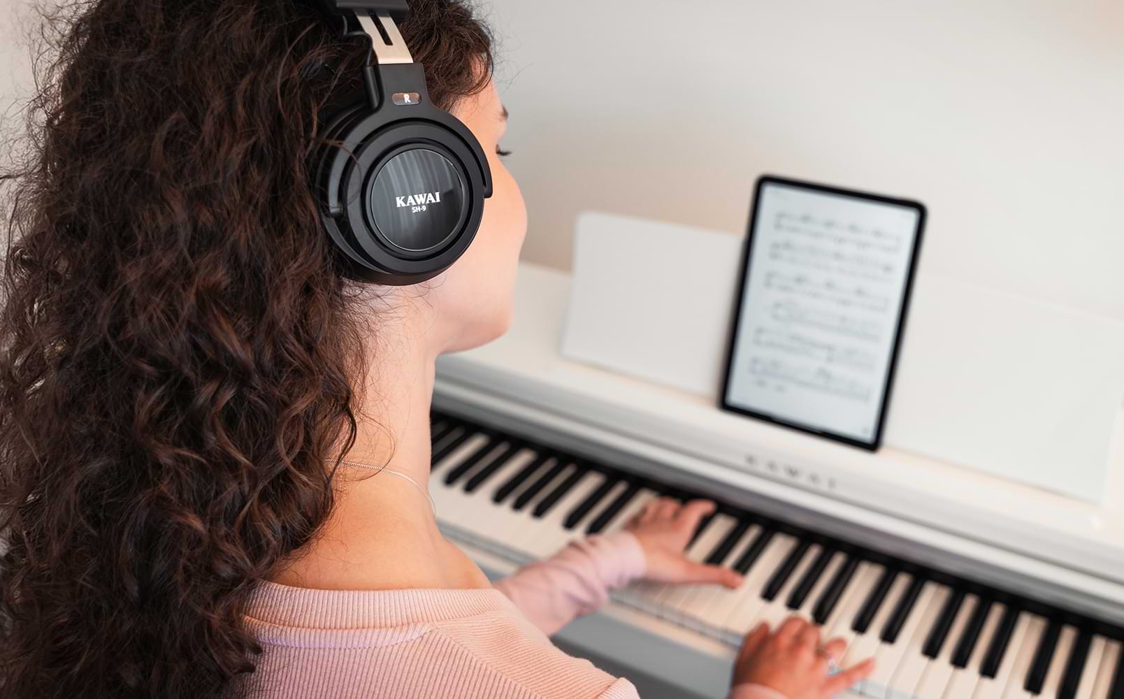A young woman playing the CX102 digital piano with headphones